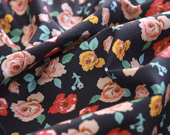May include: Close-up of a dark blue fabric with a floral pattern. The fabric is covered in small pink, red, and yellow roses with green leaves.