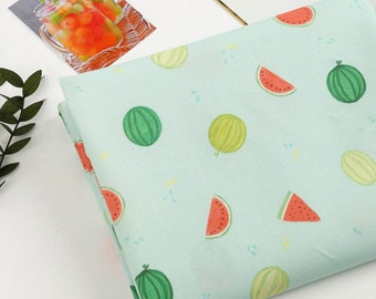 May include: A light blue fabric with a repeating pattern of watermelons and cantaloupes. The watermelons are red and green, and the cantaloupes are yellow and green.