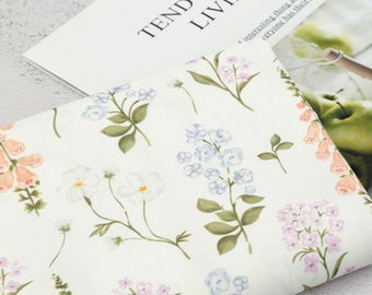 May include: White fabric with a floral print featuring pink, blue, and orange flowers. The fabric has a delicate, watercolor-like design.