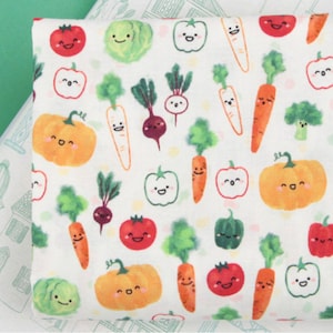 Peut inclure: Tissu blanc avec un motif répété de légumes de dessin animé colorés avec des visages heureux. Les légumes comprennent des carottes, des citrouilles, des tomates, des poivrons et des choux.