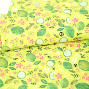 May include: Yellow fabric with a repeating pattern of green limes, pink flowers, and green leaves.
