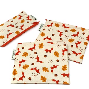 May include: Three zippered pouches with a cream background and a repeating pattern of orange foxes, brown acorns, orange leaves, and white stars. The pouches have a red zipper and a green label with the text "MyGreen Made in Canada".