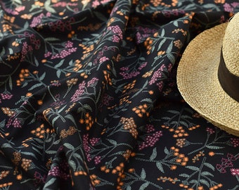 May include: Black fabric with a floral pattern in shades of orange, pink, and green. A straw hat is partially visible in the top right corner of the image.