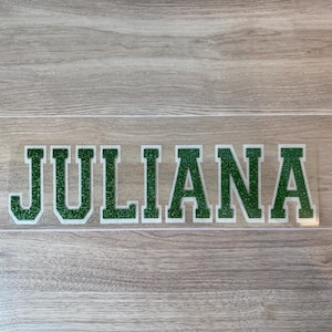 May include: A clear vinyl sticker with the name "JULIANA" in green glitter letters.