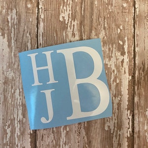 May include: White vinyl decal with the letters "HB" and a smaller "J" underneath on a light blue background.