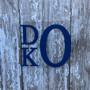 May include: Blue wooden letters spelling out "D.O.K." on a weathered wood background.
