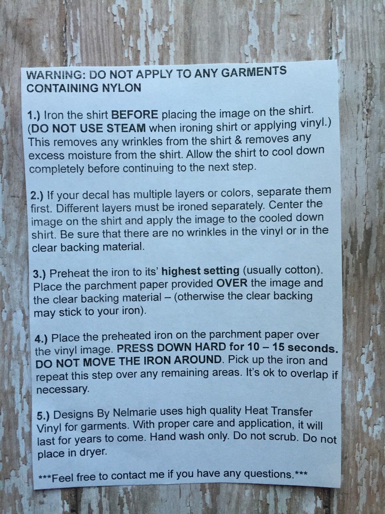 Op de afbeelding: Een wit vel papier met zwarte tekst met instructies voor het aanbrengen van hittetransferfolie op een shirt. De tekst bevat waarschuwingen over het gebruik van stoom en het aanbrengen op nylon kleding. De tekst bevat ook instructies voor het aanbrengen van de folie, inclusief het hard drukken voor 10-15 seconden.
