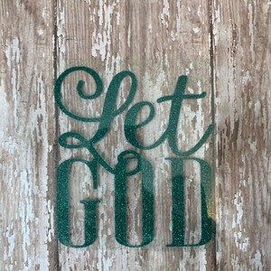 Op de afbeelding: Let God in groene glitterletters op een verweerde houten achtergrond.