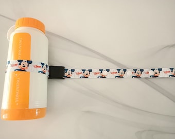 May include: A white water bottle with an orange lid and a Mickey Mouse design strap. The strap has white buttons and the text "Disney" printed on it. The bottle has the text "Yongneng" printed on it.