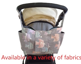 May include: A gray stroller organizer with a colorful bird print design. The organizer has multiple pockets and is attached to the stroller handle.
