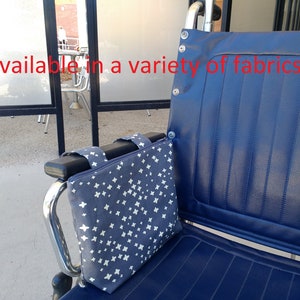 Op de afbeelding: Een blauwe rolstoel met een grijze en witte gepatenteerde stoffen armleuningshoes. De tekst "Available in a variety of fabrics" is zichtbaar in de afbeelding.