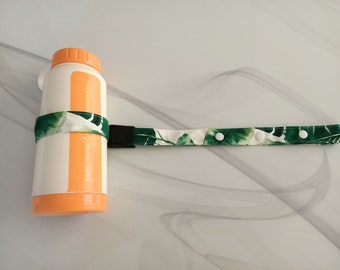 May include: A white water bottle with an orange lid and a green and white patterned strap with white buttons. The strap is attached to the bottle with a black buckle. The bottle has the text "DONGNENG PACKAGING" printed on the side.