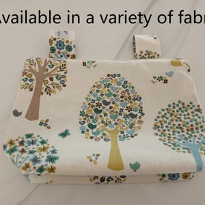 May include: A white fabric storage bin with a tree and bird pattern. The bin has two loops at the top for hanging.