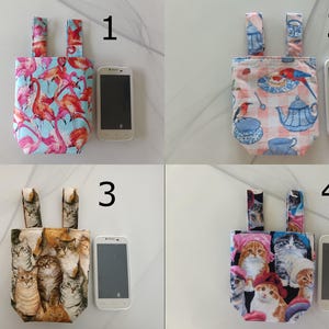 Puede incluir: Cuatro pequeñas bolsas de tela con asas, cada una con un patrón único. Los patrones incluyen flamencos, tazas de té y pájaros, un collage de gatos y gatos con sombreros. Un teléfono inteligente está al lado de cada bolsa.