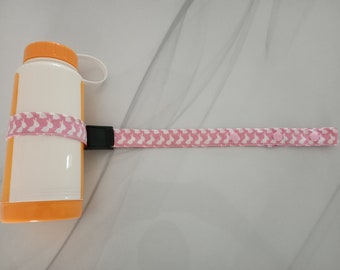 May include: A white water bottle with an orange lid and a pink strap with white bunny prints. The strap has pink buttons.