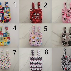 Könnte beinhalten: Neun verschiedene Stofftaschen mit verschiedenen Disney-Charakter-Drucken. Die Taschen haben zwei Schlaufen oben zum Aufhängen. Die Taschen sind von 1 bis 9 nummeriert.