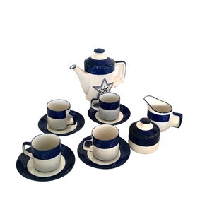 Puede incluir: Un juego de té de cerámica azul y blanco con una tetera, una jarra de crema, un azucarero y cuatro tazas y platillos. El juego presenta un diseño de estrella.
