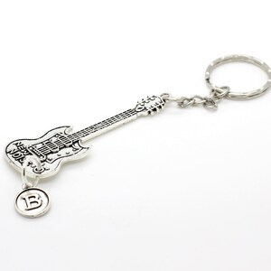 May include: Silver guitar keychain with a small charm that says "B" hanging from it. The guitar has the words "New York" on it.