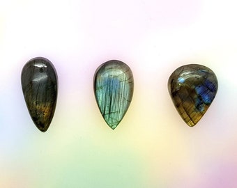 Puede incluir: Tres piedras de labradorita en forma de lágrima con reflejos iridiscentes azules, verdes y dorados.