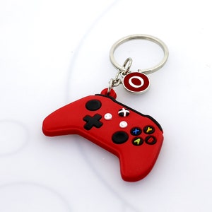 May include: Red plastic video game controller keychain with a silver key ring and a red circle charm with the letter "O" on it.
