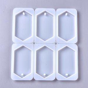 May include: A white silicone mould with six hexagonal shapes, each with a small hole at the top. The mould is designed for making resin jewellery pendants.