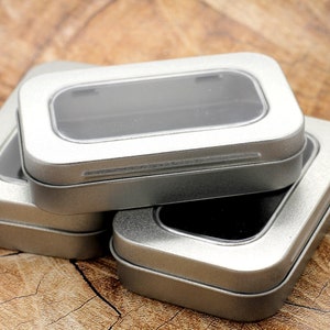May include: Three silver metal boxes with clear plastic lids. The top box has a clear plastic window.