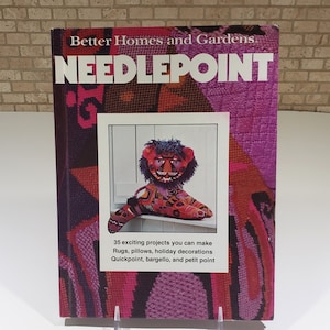 May include: A book titled "Better Homes and Gardens Needlepoint" with a colorful needlepoint lion on the cover. The book features 35 projects including rugs, pillows, holiday decorations, quickpoint, bargello, and petit point.