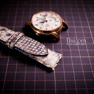 K&ouml;nnte beinhalten: Ein hellbraunes Lederarmband mit einem strukturierten Muster. Das Armband liegt auf einer schwarzen Gitteroberfl&auml;che. Der Text "Unicorn handcrafted leather" ist in der unteren rechten Ecke des Bildes sichtbar.