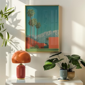 May include: A mid-century modern style interior scene featuring a framed art print of palm trees and mountains. A burnt orange table lamp sits on a white surface, with potted plants to the right. The art print has a gold frame.