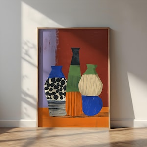 Puede incluir: Una impresión artística enmarcada que presenta una naturaleza muerta de jarrones estilizados. Los jarrones son en tonos de azul, verde, naranja y beige, sobre un fondo rojo y morado. La obra de arte se exhibe sobre un suelo de madera.