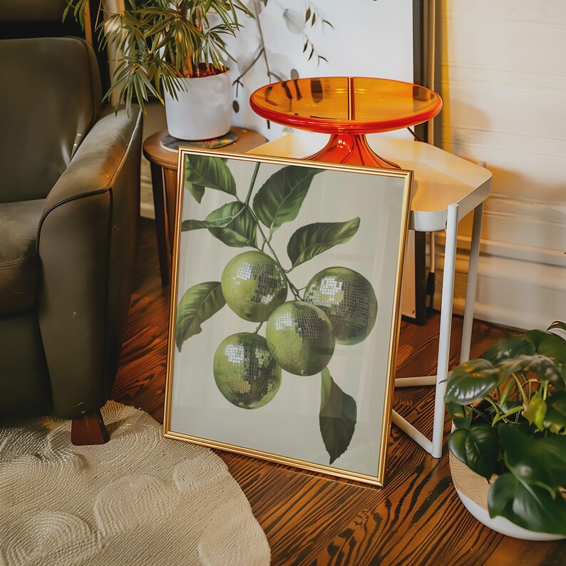 K&ouml;nnte beinhalten: Ein gerahmter Druck eines gr&uuml;nen Zitruszweigs mit f&uuml;nf Limetten. Der Rahmen ist golden und der Hintergrund ist hellgr&uuml;n. Der Druck befindet sich auf einem Tisch mit einer wei&szlig;en Oberfl&auml;che.