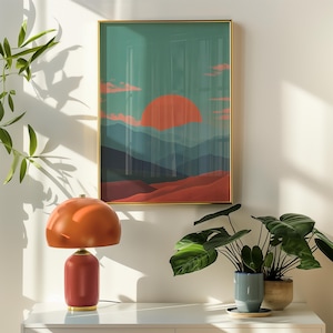May include: A modern interior scene featuring a red and orange table lamp with a rounded shade and a framed landscape art print. The artwork depicts a sunset over layered mountains. Potted plants add a touch of nature to the decor.