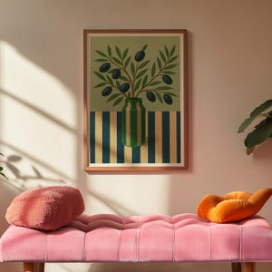 May include: A framed art print featuring a green vase with olive branches and black olives. The vase has green and white stripes, set against a striped background of blue and yellow. The print is in a wooden frame, above a pink bench with two decorative pillows.