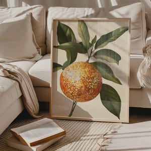 K&ouml;nnte beinhalten: Ein gerahmter botanischer Druck mit einer gro&szlig;en orangefarbenen Frucht mit strukturierter Oberfl&auml;che, umgeben von gr&uuml;nen Bl&auml;ttern.