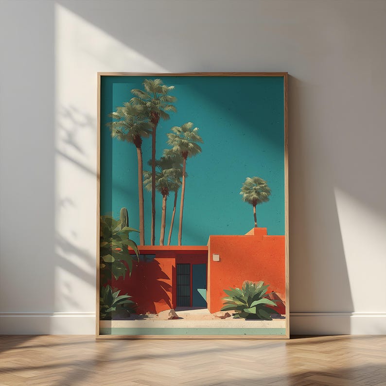 May include: Framed art print featuring a mid-century modern style scene. The artwork depicts a vibrant orange building with a teal sky and tall palm trees. Green plants and a sandy area complete the desert landscape. The print is in a wooden frame.