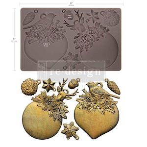 May include: A brown silicone mold measuring 8 inches by 5 inches, featuring cavities for casting holiday-themed ornaments including a bird, deer, pinecones, and snowflakes. Below the mold are gold-colored finished castings of these same shapes.