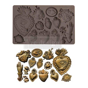May include: A brown silicone mold featuring various heart designs, hands, and floral elements. The mold includes sacred heart motifs, crosses, and eye symbols. The finished products are shown in a metallic gold color.