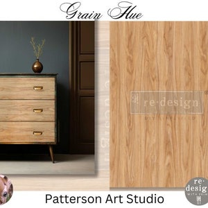 May include: A four-drawer dresser with a wood grain finish. The dresser has a light brown wood grain pattern and is painted a light blue color. The dresser is sitting on a dark gray floor. The text "Grain Hue" is at the top of the image. The text "re-design" is in the center of the image. The text "Patterson Art Studio" is at the bottom of the image.