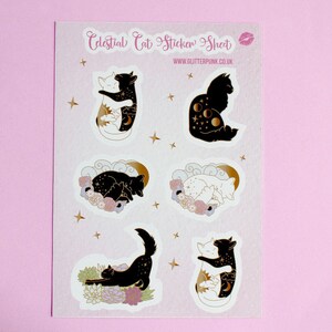 May include: A sheet of stickers featuring celestial cat designs. The stickers are white with gold accents and feature cats with moon, stars, and sun imagery. The sheet is labeled "Celestial Cat Sticker Sheet" and "www.glitterpunk.co.uk".