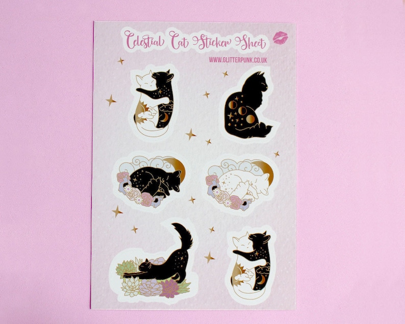 May include: A sheet of stickers featuring celestial cat designs. The stickers are white with gold accents and feature cats with moon, stars, and sun imagery. The sheet is labeled "Celestial Cat Sticker Sheet" and "www.glitterpunk.co.uk".