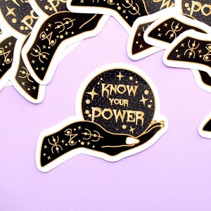 May include: A collection of stickers with a black and gold design. The central sticker features a hand holding a crystal ball with the words "KNOW YOUR POWER" in gold lettering. The background is a starry night.