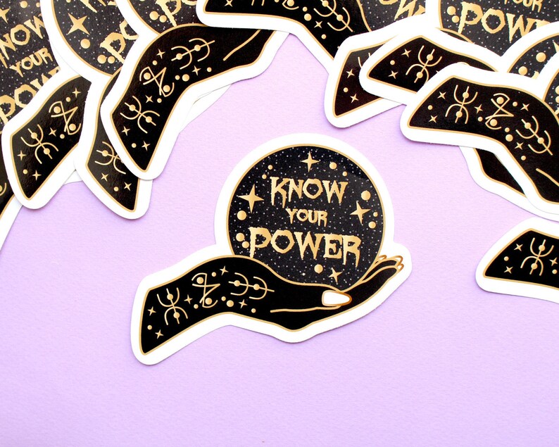 May include: A collection of stickers with a black and gold design. The central sticker features a hand holding a crystal ball with the words "KNOW YOUR POWER" in gold lettering. The background is a starry night.