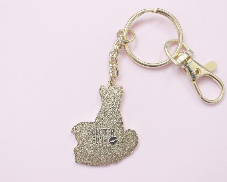 May include: Gold-colored keychain with a cat-shaped charm. The charm has the text "GLITTER PUNK" and a lipstick kiss mark. The keychain includes a split ring, a chain, and a lobster clasp for easy attachment.