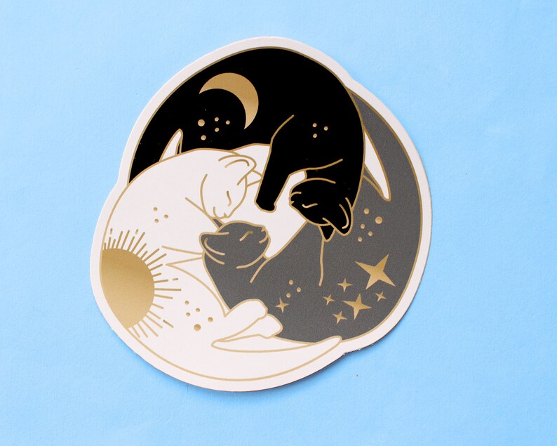 Pu&ograve; includere: Un adesivo con un design stilizzato di tre gatti in una disposizione yin-yang. Il gatto in alto &egrave; nero con una luna crescente dorata, il gatto in basso &egrave; bianco con un sole dorato e il gatto centrale &egrave; grigio. Sono incluse stelle e punti dorati.