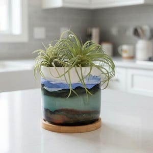 May include: A set of three ceramic nesting bowls in shades of blue, green, and white. The bowls feature a speckled glaze and a simple, modern design. The largest bowl measures approximately 8 inches in diameter.