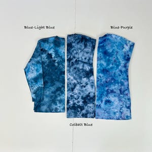May include: Three tie-dye shirts in shades of blue. The shirts are labeled "Blue-Light Blue", "Cobalt Blue", and "Blue-Purple". The long-sleeved shirt is on the left, a sleeveless shirt is on the right, and a sleeveless shirt is in the middle.