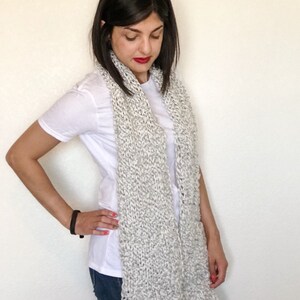 This scarf is knit with gray and white intertwined acrylic yarn.