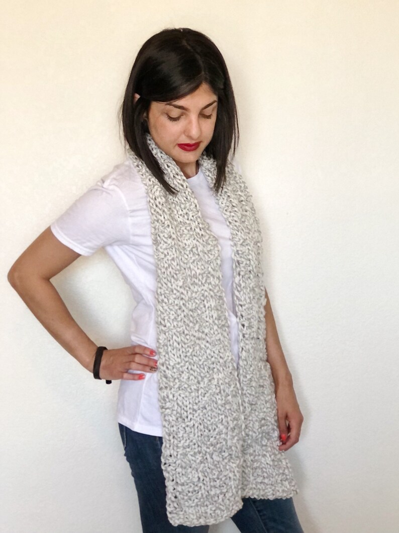 This scarf is knit with gray and white intertwined acrylic yarn.