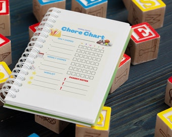 May include: A white chore chart with a green and white spiral binding. The chart has sections for daily chores, weekly chores, a wishlist, and parent notes. The chart is surrounded by colorful wooden blocks with letters on them.