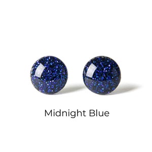 May include: A pair of round, midnight blue glitter stud earrings.